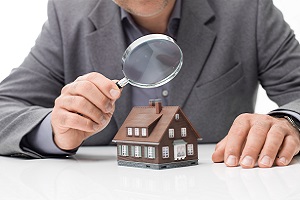 Man holding magnifying glass over model of a  home